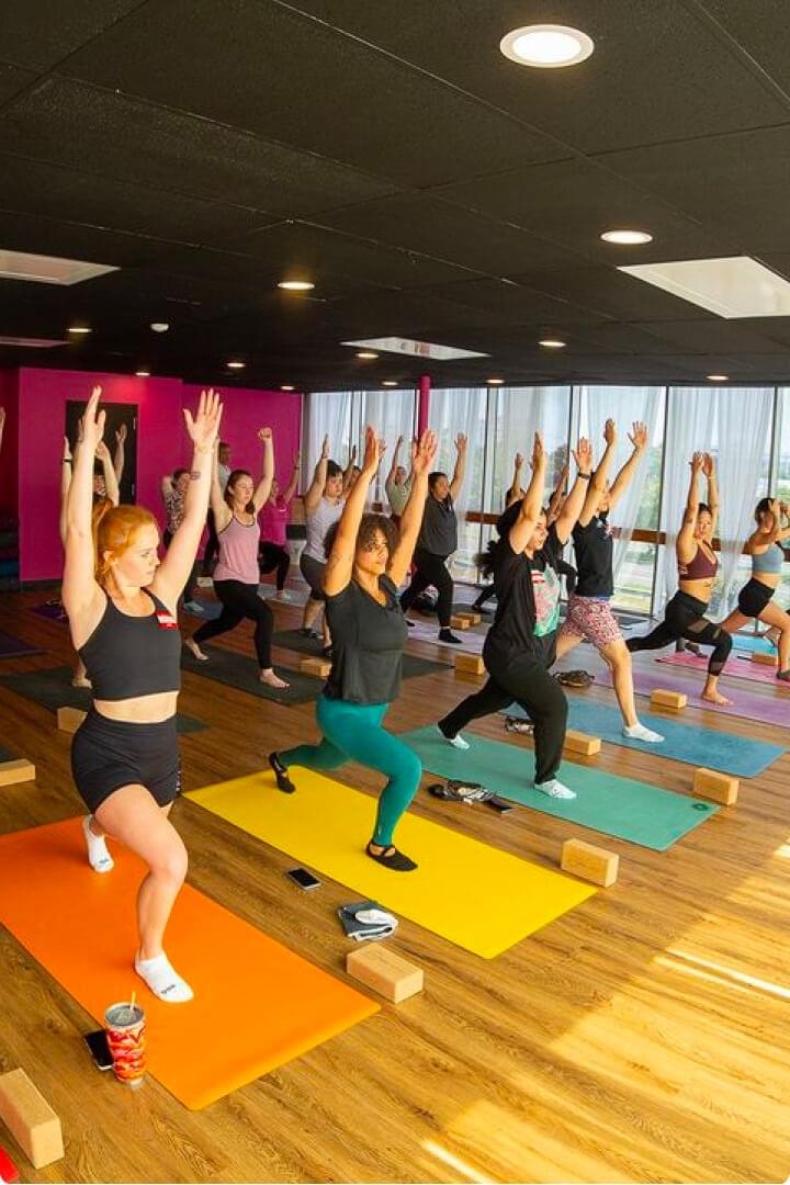 Multicultural crowd engaging in yoga poses inside a room with ample space.
